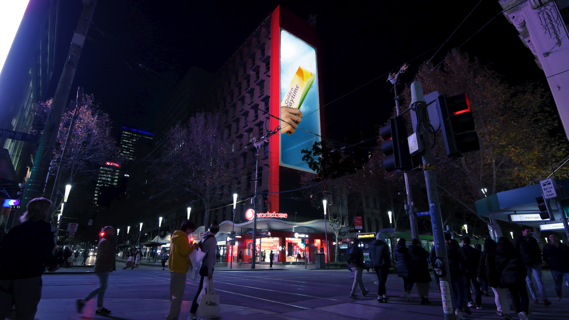 Golden Gaytime billboard illuminating a Melbourne street at night